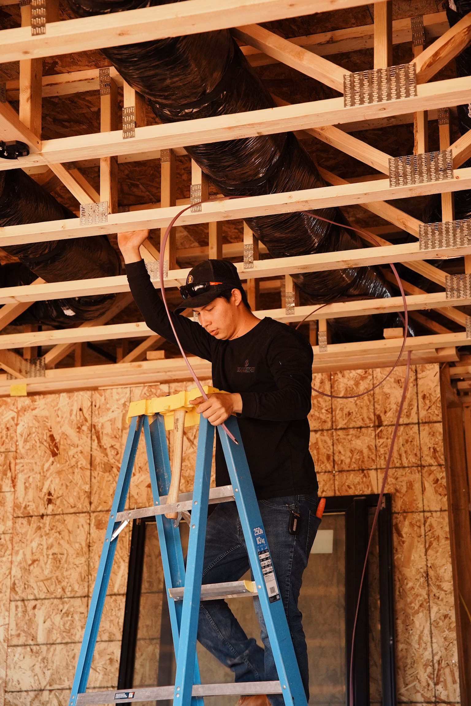 A Blackstone Electrical crew member running low-voltage wire during a residential rough-in