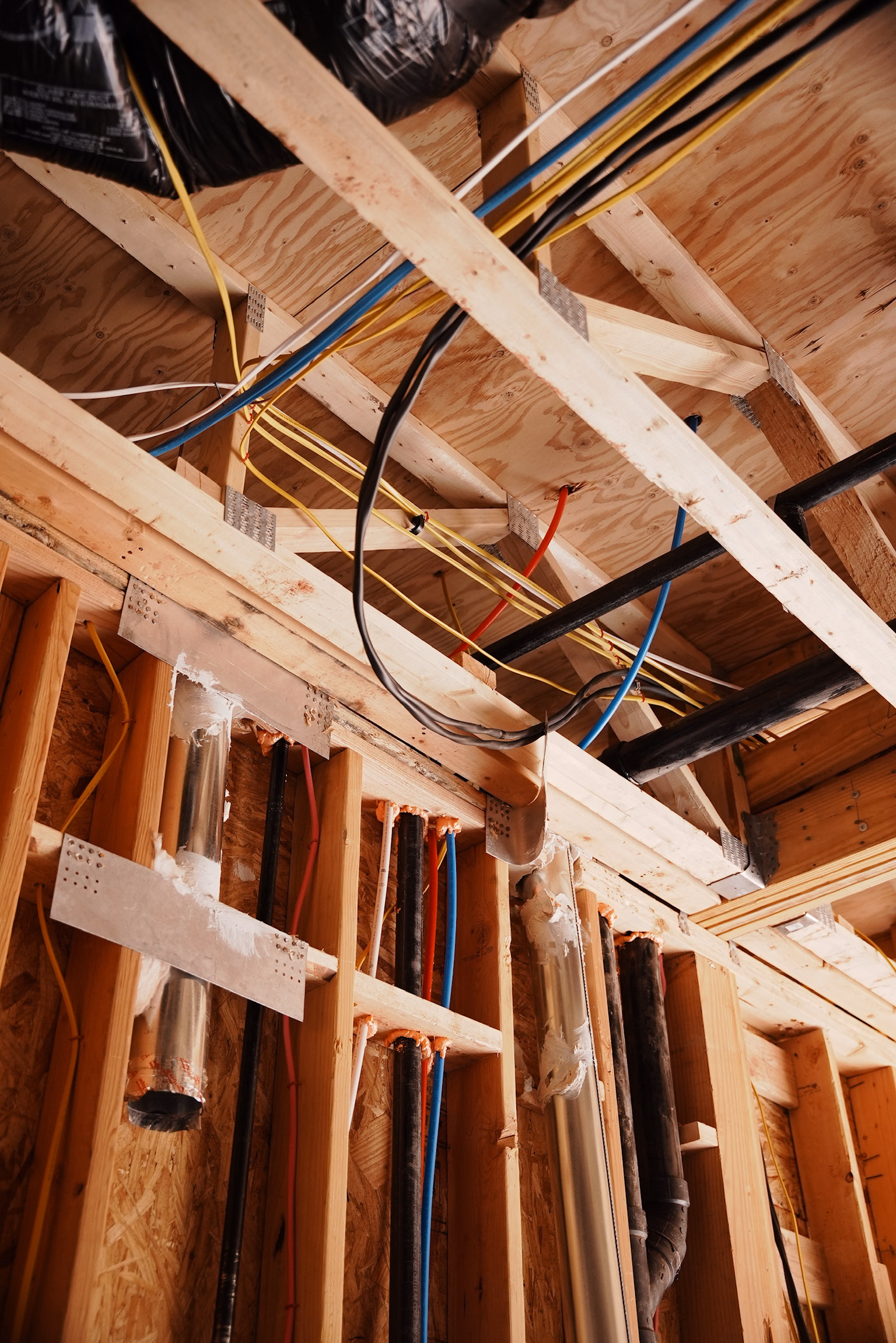 Multi-color rough-in wiring routed through framed walls with conduit and electrical boxes visible